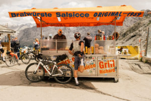 French skate filmmaker Ben Chadourne stretches at a Bratwurste stand at the top of Stelvio pass